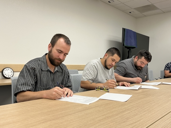 Three men sign papers at a table