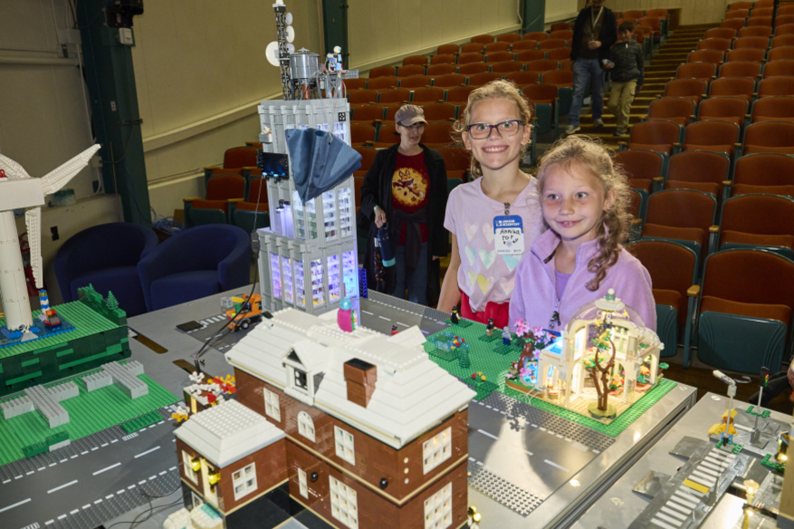 Two girls standing near a LEGO simulation of a city